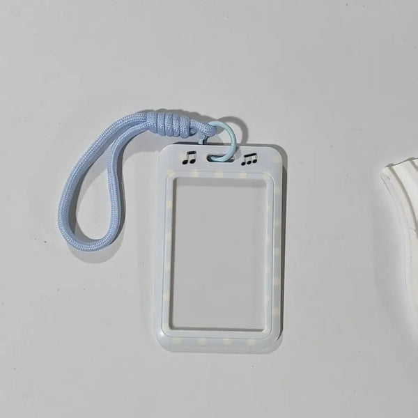 A white card holder with a clear plastic cover and a light blue lanyard attached.