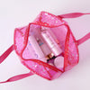 A pink clear waterproof makeup organizer bag containing various cosmetic products and a round compact.