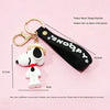 A black keychain featuring a white Snoopy figure attached to a gold ring.