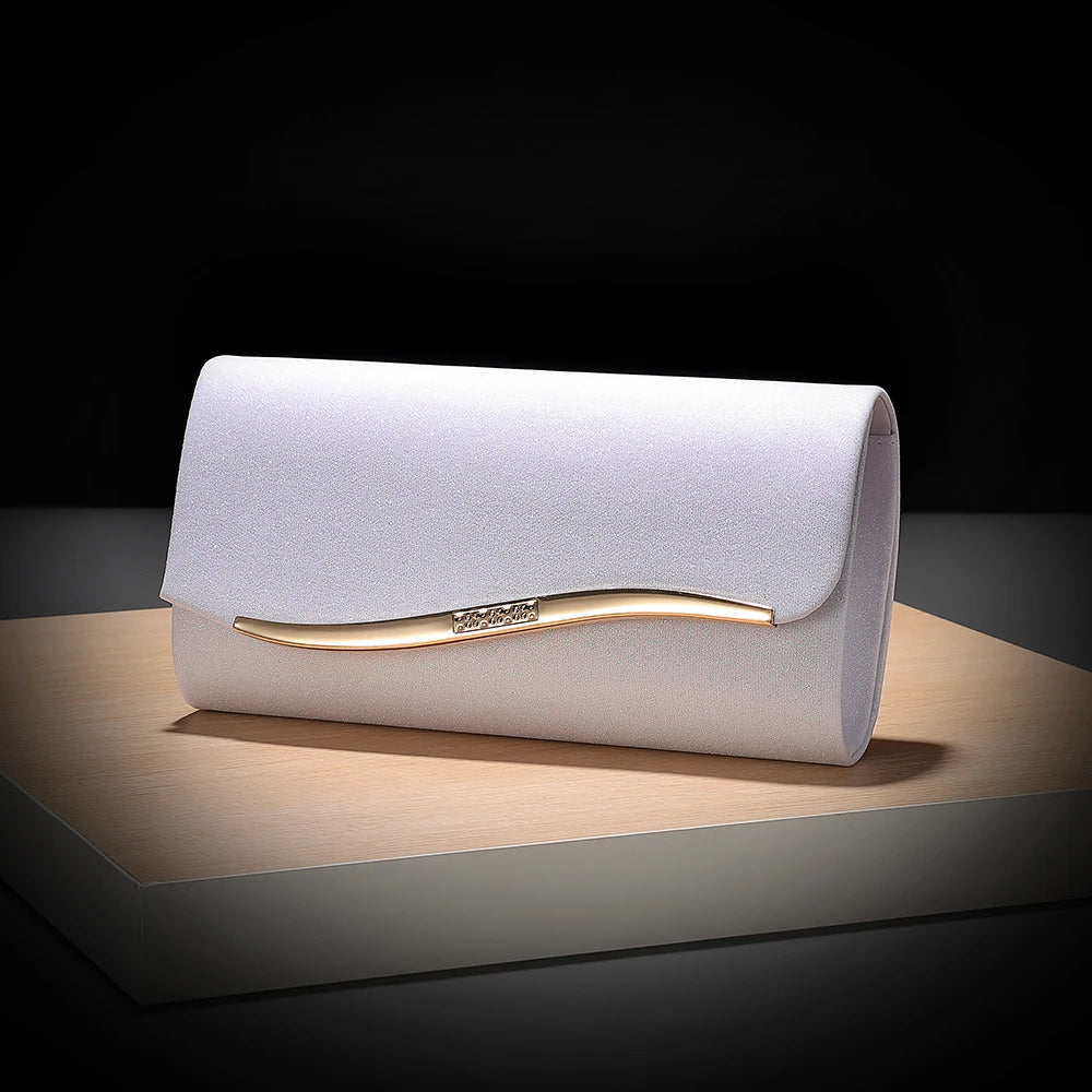 A light purple envelope clutch with a gold-toned chain detail resting on a wooden surface.