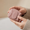 A hand holds a pink, lychee-textured coin purse with a snap closure against a light background.