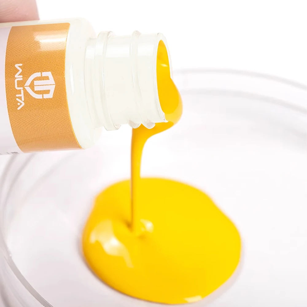 Une bouteille d'huile de peinture pour cuir professionnelle verse un liquide jaune vif dans un récipient transparent.