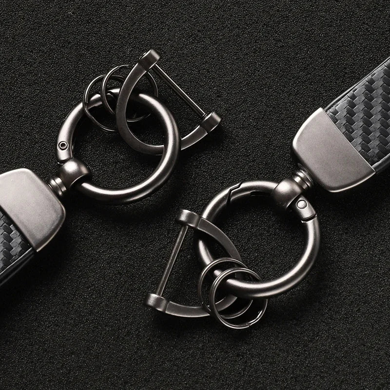 A close-up of a silver carbon fiber leather keychain with a metal clasp and ring.