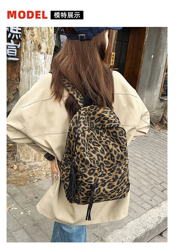A woman is shown from the back wearing a beige oversized shirt and a leopard print canvas backpack.