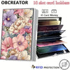A metal card holder with a floral design featuring pink and purple flowers, displaying various cards and money.