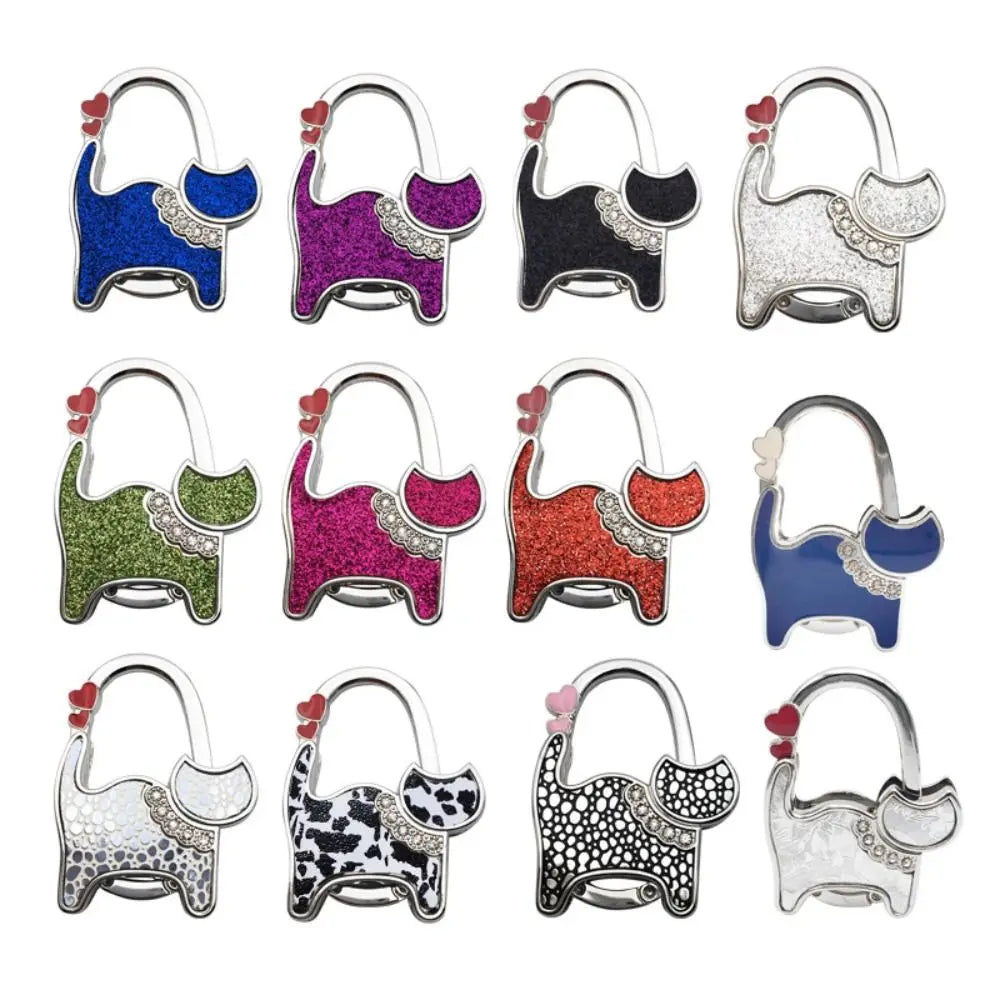 A set of twelve portable cat handbag hooks in various colors and glitter finishes for table hanging.