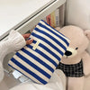 Un clutch à tissage rayé bleu marine et blanc, à côté d'un grand jouet rose.
