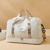 A cream-colored durable nylon travel duffle bag with light brown straps and a gold accent.