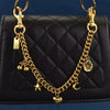 A black quilted shoulder bag with a gold chain necklace featuring cherry flower and crescent moon charms