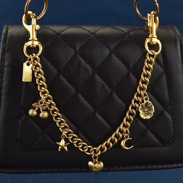 A black quilted shoulder bag with a gold chain necklace featuring cherry flower and crescent moon charms