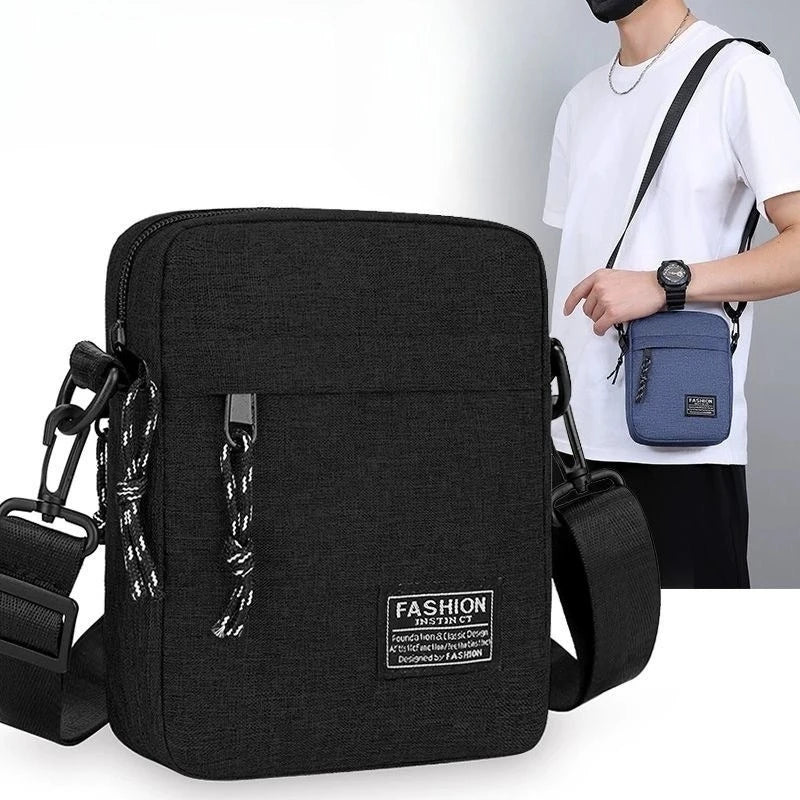 Eine schwarze, kompakte Crossbody-Tasche mit dunkelblauer Akzentfarbe und schwarzem Riemen neben einem weißen T-Shirt.
