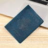 A dark blue leather passport holder with embossed eagle design resting on a light wooden surface.