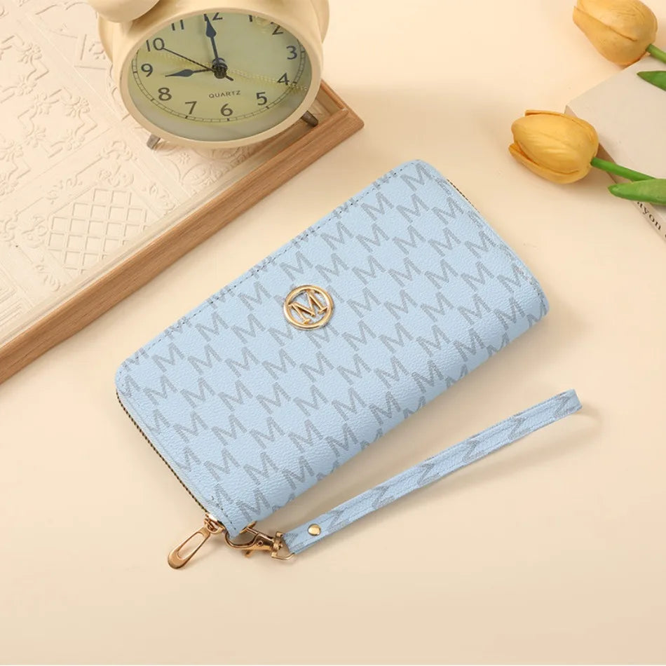 A light blue quilted zipper wallet with a gold accent is shown next to a vintage-style clock and a yellow tulip.