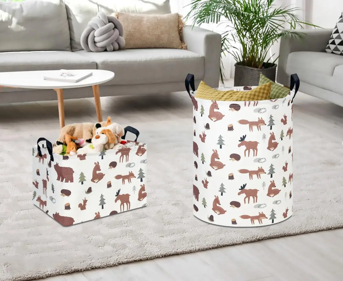 A white fabric storage basket with handles decorated with woodland animal silhouettes on a light gray rug.