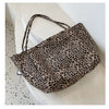 A leopard print canvas crossbody tote bag is displayed on a white surface.