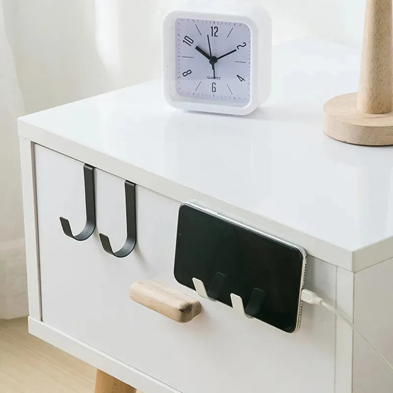 A white clock and a black hook rack are displayed on a white cabinet top.