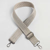 A beige woven strap with an arrow jacquard pattern, shown crossed on a white background.