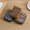 A set of three leopard print PU leather compact wallets in various shades of brown and black resting on a wooden surface.