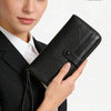 A woman holds a black PU leather zipper clutch wallet with a protective RFID shield.