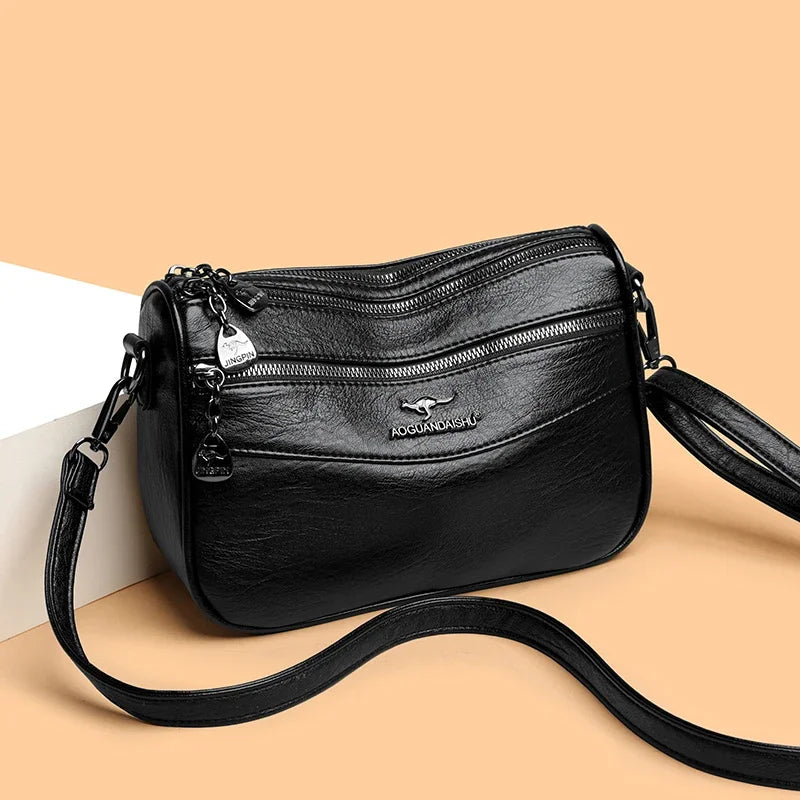 Bolso cruz de cuero negro para mujer con dije plateado y correa negra.