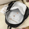 Un sac à dos noir à pois ouvert, montrant sa poche zippée.