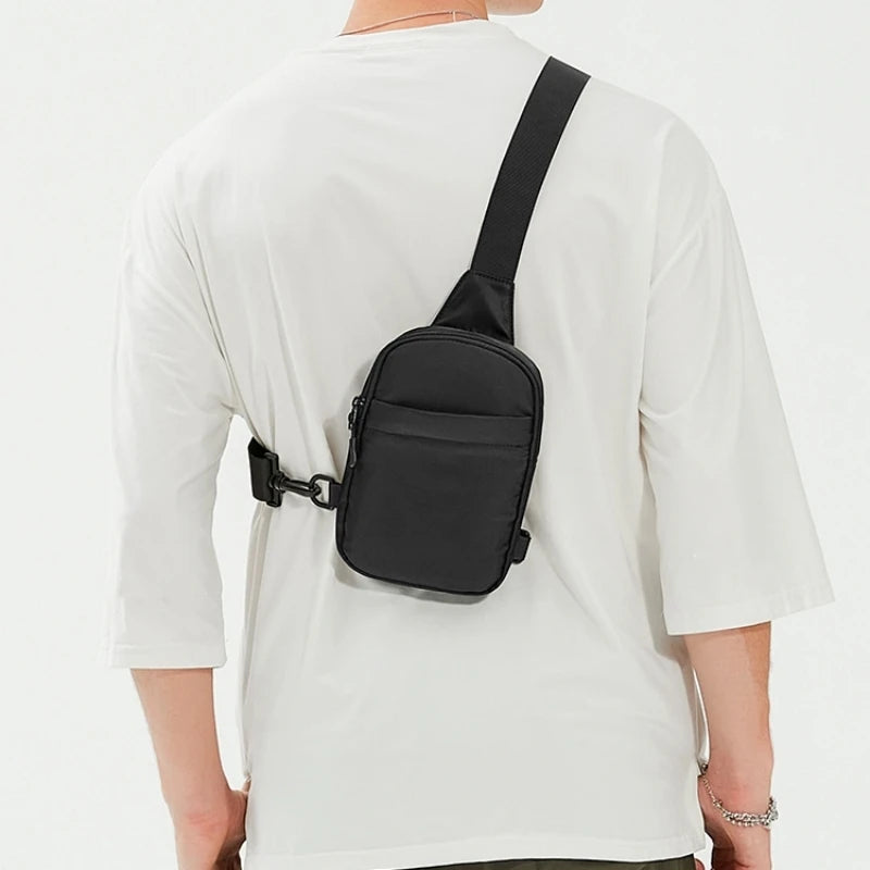 Una bolsa cruzada negra multifuncional llevada sobre una camiseta blanca.