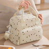 Un sac à pique-nique portable en velours côtelé de couleur crème tenu par une personne.