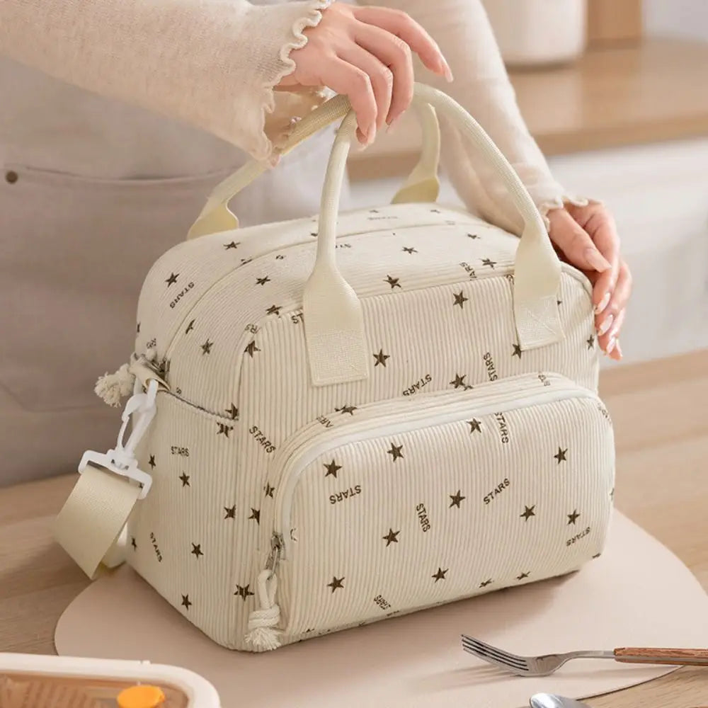 Un sac à pique-nique portable en velours côtelé de couleur crème tenu par une personne.