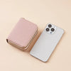 A pink quilted zippered wallet is shown next to a white smartphone on a light background.
