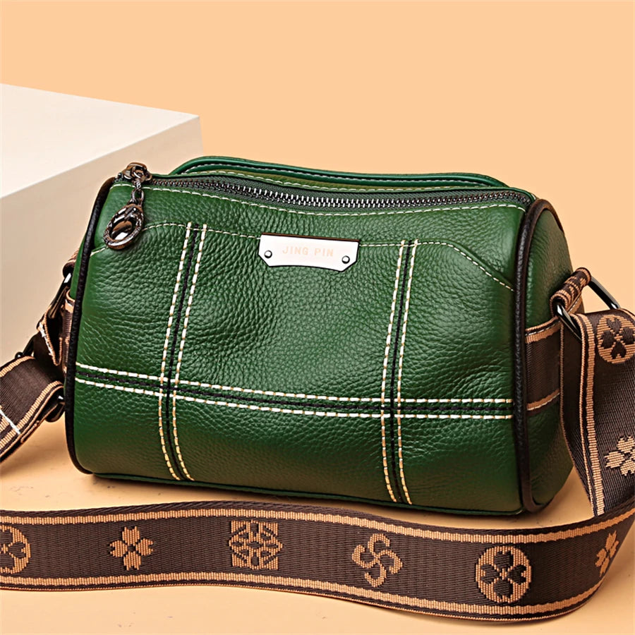 A dark green luxury cowhide shoulder bag with brown leather strap and white stitching.