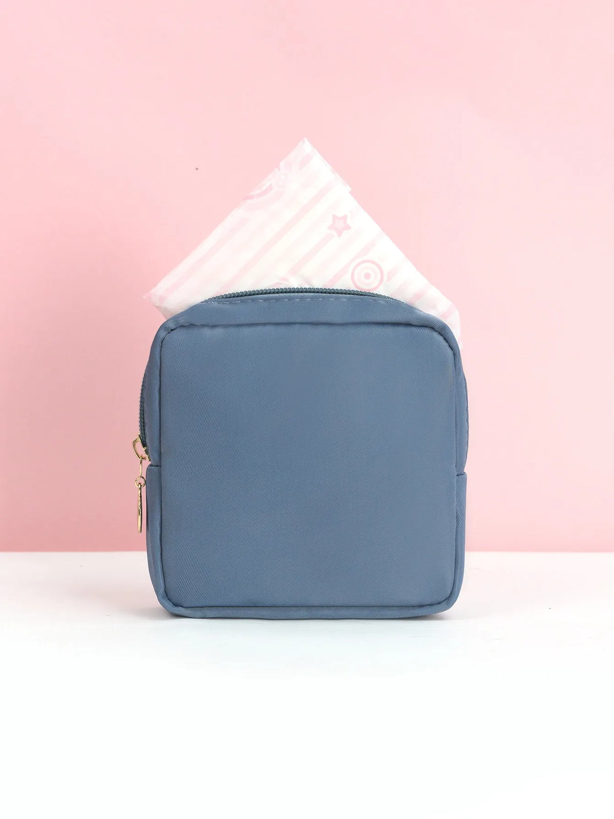 Schieferblaue tragbare Tasche zum Aufbewahren von Tampons, mit einem rosa gemusterten Tampon sichtbar.