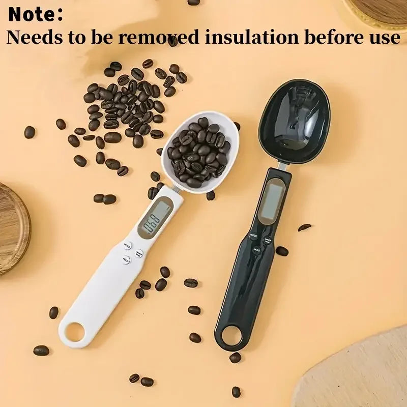 A black digital kitchen scale is shown next to spilled coffee beans on a light background.