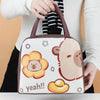 A brown insulated lunch bag featuring a cartoon capybara face and the text yeah!