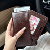A hand holds a brown leather passport wallet with RFID blocking features and a passport inside.