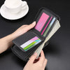 A hand is opening a black zippered wallet displaying various credit cards and cash next to a white cup on a dark surface.