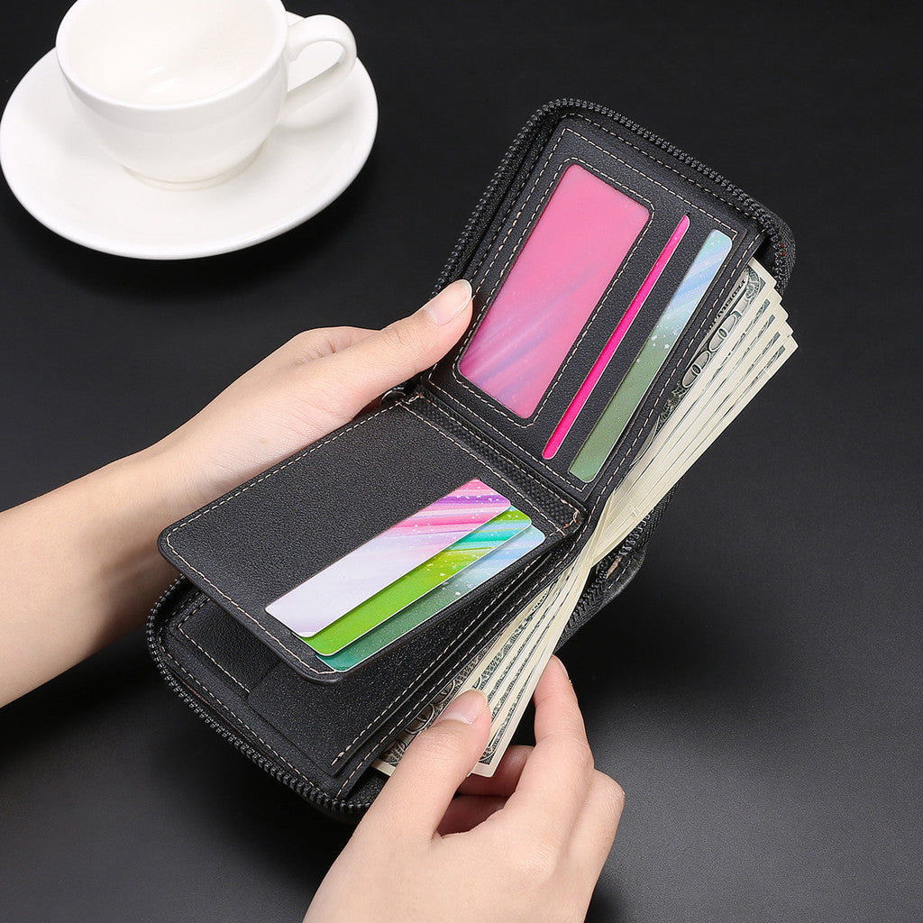 A hand is opening a black zippered wallet displaying various credit cards and cash next to a white cup on a dark surface.